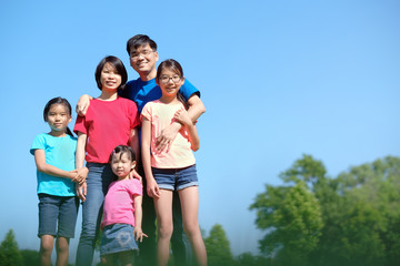 Happy Asian family with children outdoors in park during summer