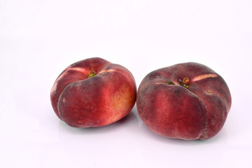 Zwei Plattpfirsiche (Bergpfirsich).  Prunus persica var. platycarpa. Freigestellt vor weißem Hintergrund