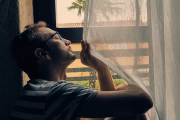 Silhouette of lonesome man looking through the window.