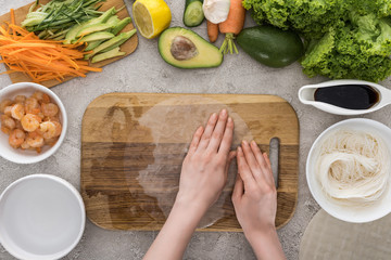 top view of woman holding rice paper on cutting board