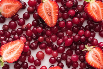 top view of red, fresh and ripe cranberries, cut strawberries