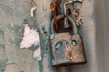 Closed old rusty lock. On the background of a metal fence in a grunge style door.