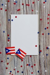 Fototapeta na wymiar Puerto Rico independence day. day of constitution 25 July. the concept of veterans Day or memorial. mini flags and confetti with sheets of white paper on a white wooden background. mockup