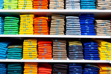 Colorful clothing neatly stacked on shelves	
