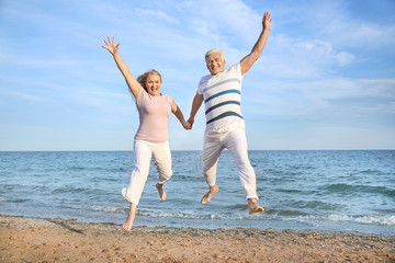 Happy jumping mature couple at sea resort