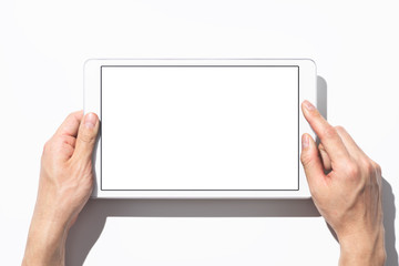 Closeup of hands touching white tablet computer on white background with shadow. Blank screen. Top view.