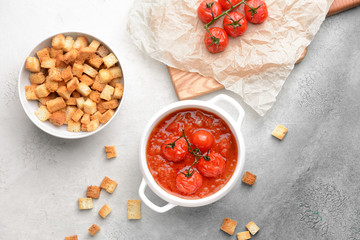 Pot of tasty tomato cream soup and croutons on light background