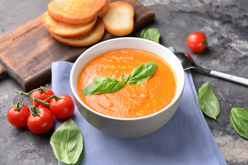 Bowl of tasty tomato cream soup on grunge background