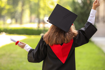 Happy young woman with diploma on graduation day