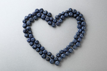 Heart made of ripe blueberry on grey background