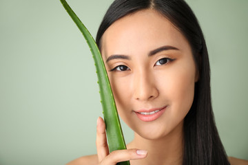 Beautiful Asian woman with aloe vera on color background