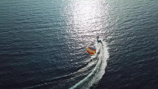 Aerial shot of a boat draging a parachute in the sea
