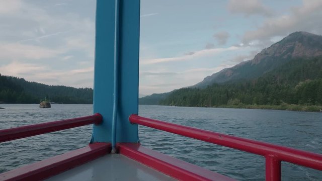 Cruise ship floating on Columbia River Gorge in Pacific Northwest Oregon with mountain scenery on a beautiful day slow motion