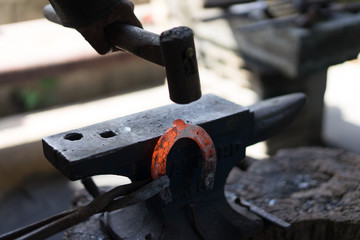 A blacksmith makes a horseshoe with a hot iron.
