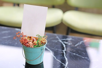 White blank paper label menu frame in mini flower pot on table at Bar restaurant.