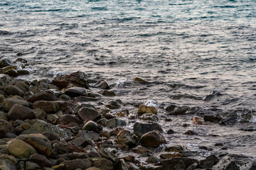 Black dark stone on the beach in the sea with a little snails all that area. It's twiligt time in Asian, Thailand.