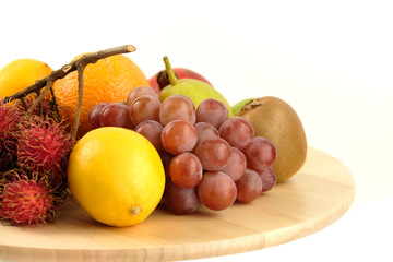 A heap of different tropical fruits isolated on Wooden tray. Healthy and organic fair concept. - Image