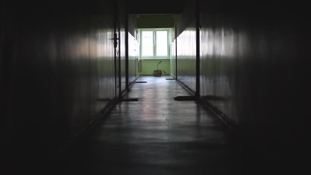 Slow motion shot in an old dark empty corridor in a block of flats, a stylized place with a window at the end of the corridor, slowly walk forward