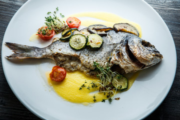 top view closeup baked fish served with sliced vegetables