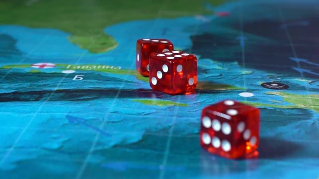 Hand throwing red dice on the world map of the playing field handmade Board games with a pirate ship. The game of battleship.
