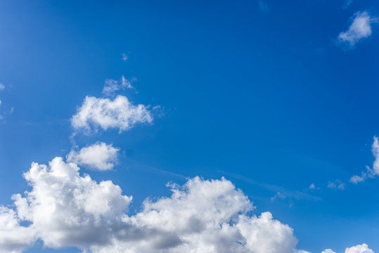 Fluffy white clouds against a bright, colorful blue sky