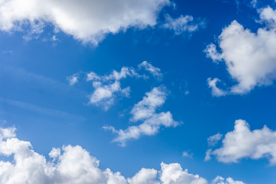 Fluffy white clouds against a bright, colorful blue sky