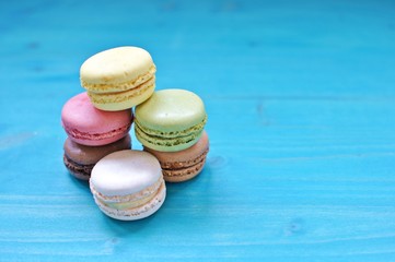Pile of colorful macaroons on blue background. Copy text.