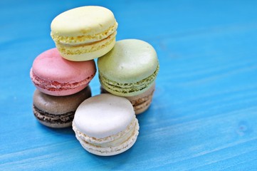 Pile of colorful macaroons on blue background. Close up, copy text.