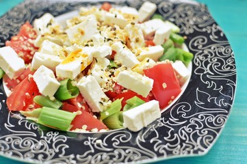 Close up of an fresh tomatoes, cheese, hemp seeds and onion salad.