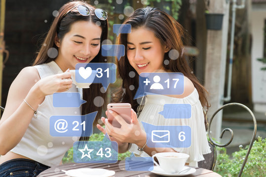 Two Beautiful freelance woman use social media on smartphone in coffee shop, chat on application
