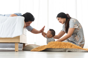 Father and 8 months old son make hi 5 with laugh and fun with mother sit behind