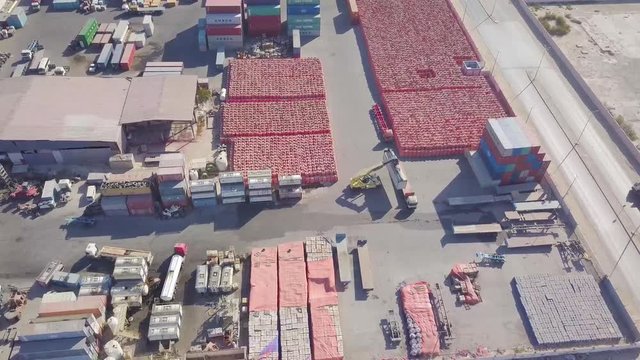 Trucks lineup to get loaded with container cargo in a container yard with a cargo lifter forklift (4K)