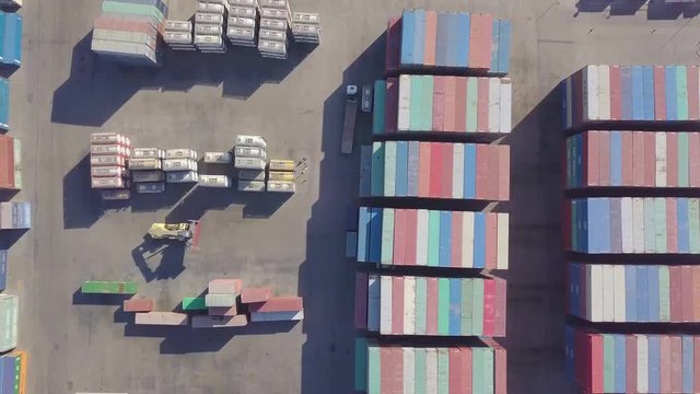 A cargo carrier moves a container through a container shipping yard and places it in another location (4K)
