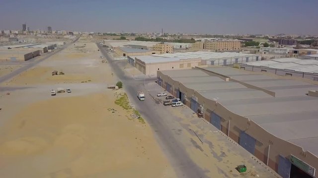 A truck driving by warehouses in the desert with large garage gate doors (4K)