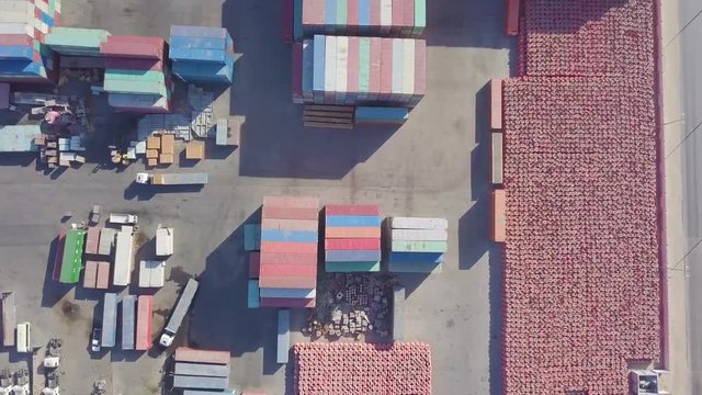 Aerial footage of a large truck moves a small package on its trailer while a forklift loads an empty container (4K)