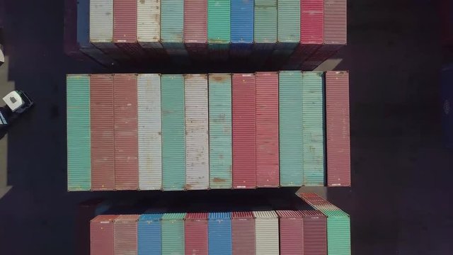 Colorful shipping containers with trucks and cargo carriers vertical zoom out (4K)