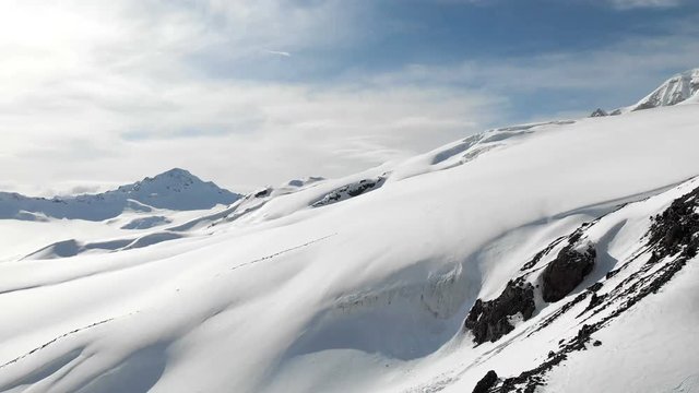Aerial view of a winter mountain landscape. The snow-covered rocky slopes of the resort of the southern Elbrus region with ski tracks on the snow. Winter sports concept