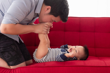 Father blow his son's feet tickle with laugh and fun