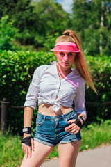 Portrait of an emotional girl in a pink cap visor and protective gloves for rollerblades and skateboarding.