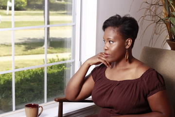 Thoughtful woman enjoying solitude with coffee by a sunlit window