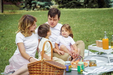 Happy family with kids resting on the grass during a picnic. Happiness and harmony in family life.
