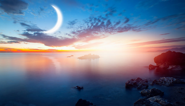 Crescent moon rising above calm sea in sunset sky "Elements of this image furnished by NASA"