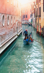 Venetian gondolier punting gondola through green canal waters of Venice Italy © muratart