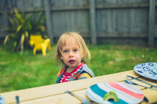 Little toddler sitting at table outdoors