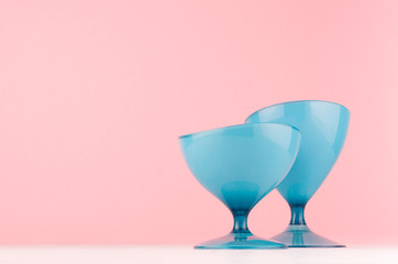 Minimalistic home decoration - glossy egg shape blue plastic vase on white wood board and pastel pink background.