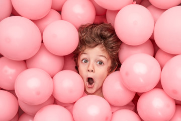 Fototapeta na wymiar Funny boy under pink balloons