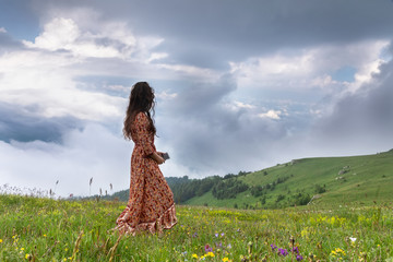Young woman with cell looking at a sky at mountains