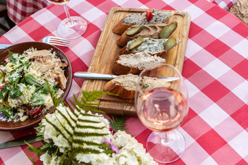 Still life with food meal as of salad, bread with different sauces, glass of rose vine and small white flower bouquet