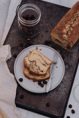 Slices of homemade vanilla stirred pound cake baked in loaf pan with cinnamon sugar and hazelnut marble swirls on rustic sheet or tray with crumbs fresh from the oven on dark background