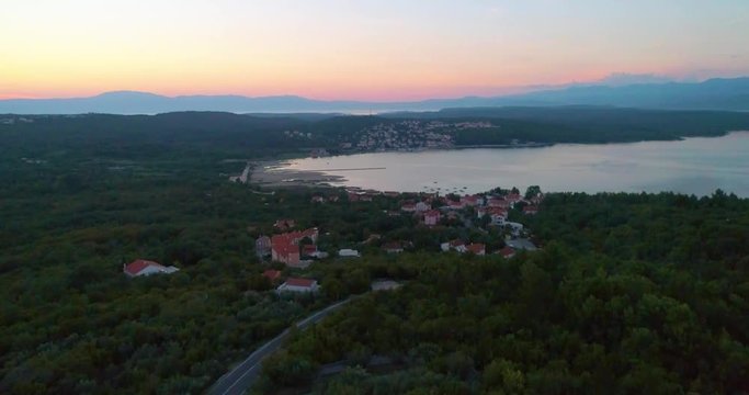 Croatian town at sunset, aerial, descending, drone shot, towards buildings and houses, in Soline village, on Krk island, at dusk, on a sunny, summer evening. in Croatia